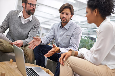 Buy stock photo Shot of a diverse group of office professionals talking around a laptop