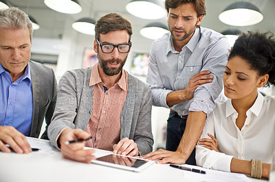 Buy stock photo Shot of a group of young professionals working at a desk in an office