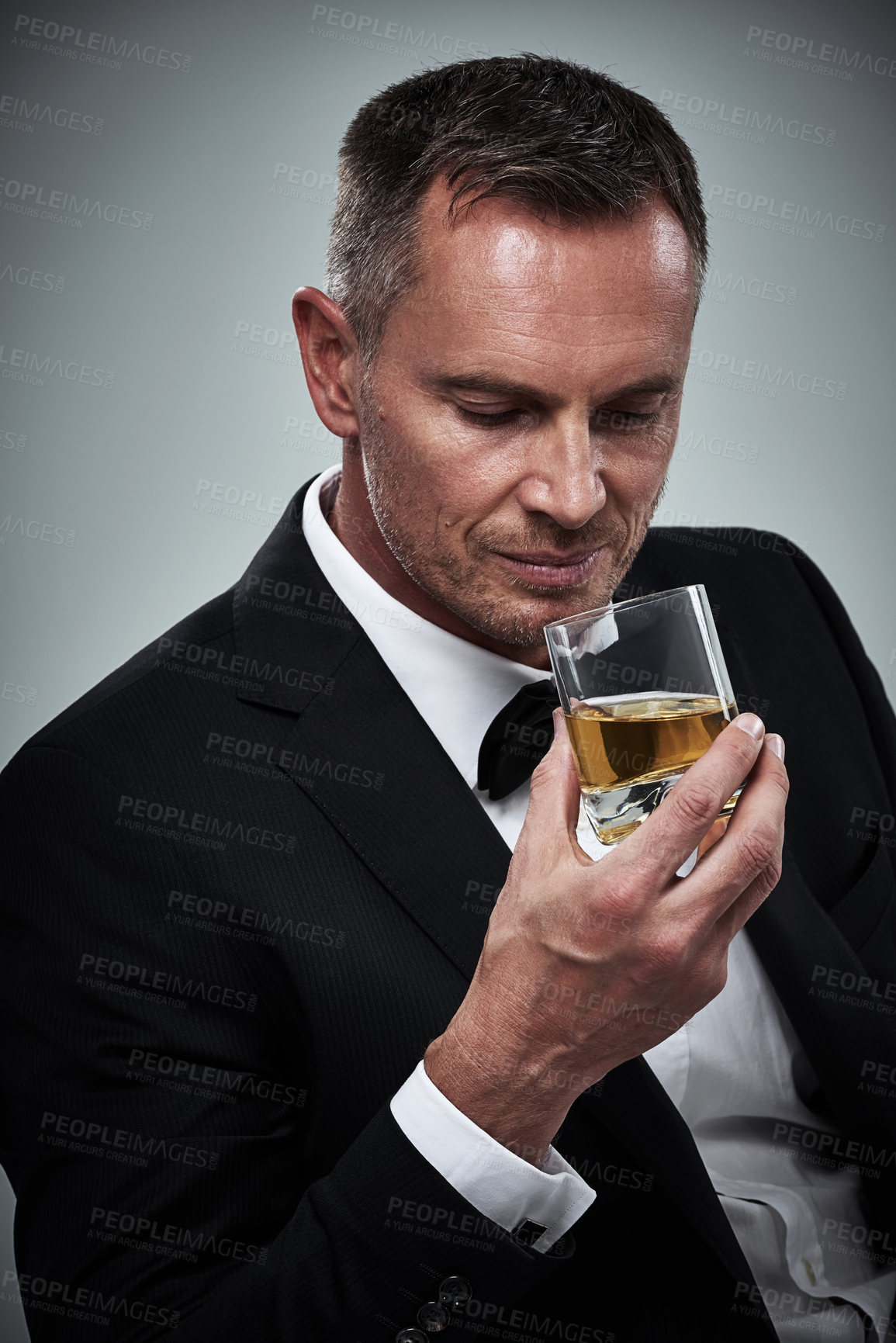 Buy stock photo Man, tuxedo fashion and whiskey in studio isolated on a gray background. Alcohol, whisky and mature male model in stylish, designer and classy suit smelling aroma of alcoholic beverage in glass.