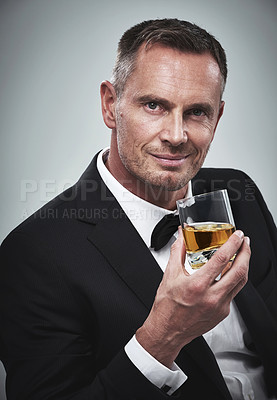 Buy stock photo Portrait, man and a glass of whisky for celebration, smile and guy on grey studio background. Face, male and gentleman in a suit, alcohol beverage or drinking for achievement, confidence or happiness