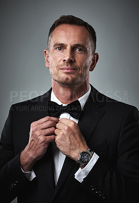 Buy stock photo Studio portrait of gentleman in tuxedo, fixing tie and serious, isolated on grey background. Luxury, fashion and and man with wealth, success and celebrity actor style, date for valentines day.