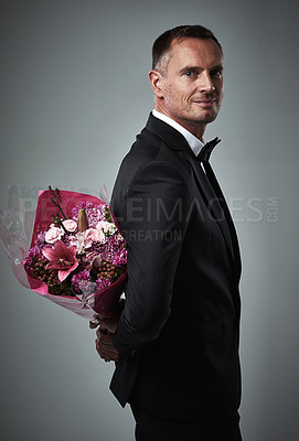 Buy stock photo Surprise, portrait and man with flowers for a date isolated on a grey studio background. Classy, gift and mature person in a suit with a bouquet of roses as a present for valentines day on a backdrop