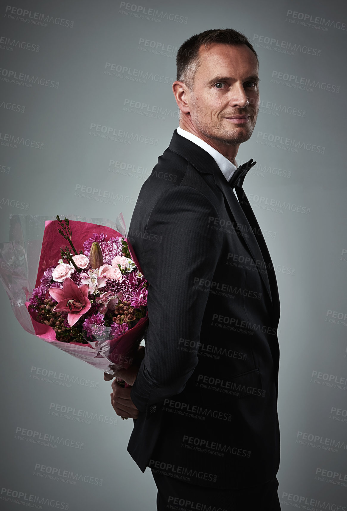 Buy stock photo Surprise, portrait and man with flowers for a date isolated on a grey studio background. Classy, gift and mature person in a suit with a bouquet of roses as a present for valentines day on a backdrop