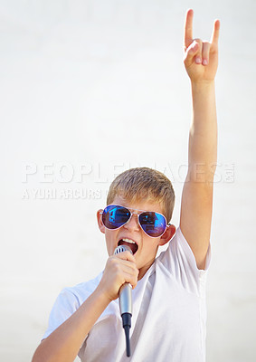 Buy stock photo Mic, rock star and kid singing in sunglasses, creative talent and cool outdoor by wall at home. Child on microphone, recording voice and music, song and sound, karaoke and technology for performance
