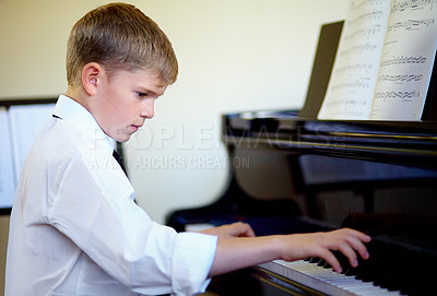 Buy stock photo Young boy playing the piano diligently