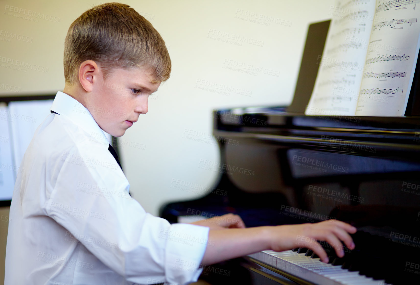 Buy stock photo Young boy playing the piano diligently