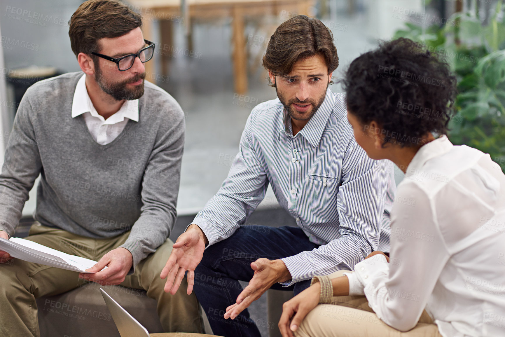 Buy stock photo Shot of a group of young professionals discussing paperwork