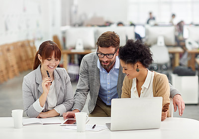 Buy stock photo Shot of a group of young office professionals talking over a digital tablet