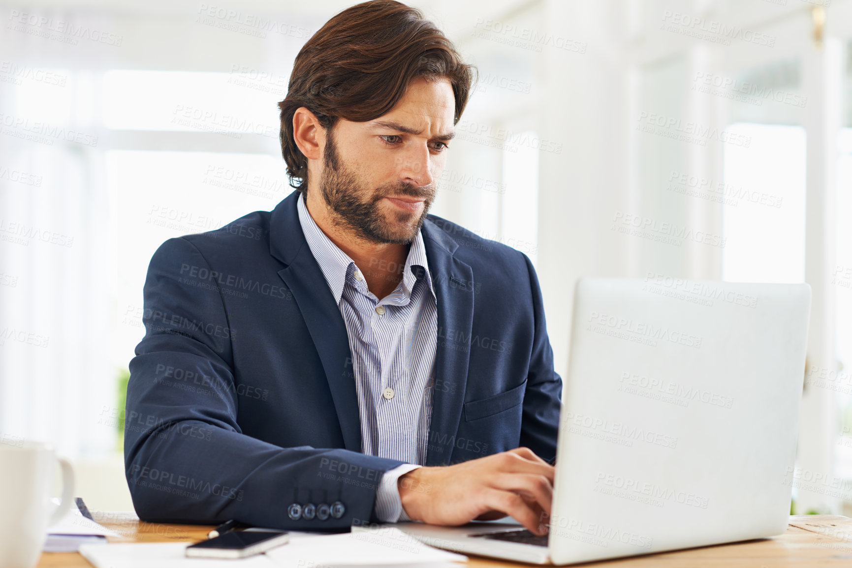 Buy stock photo A handsome businessman working on his laptop