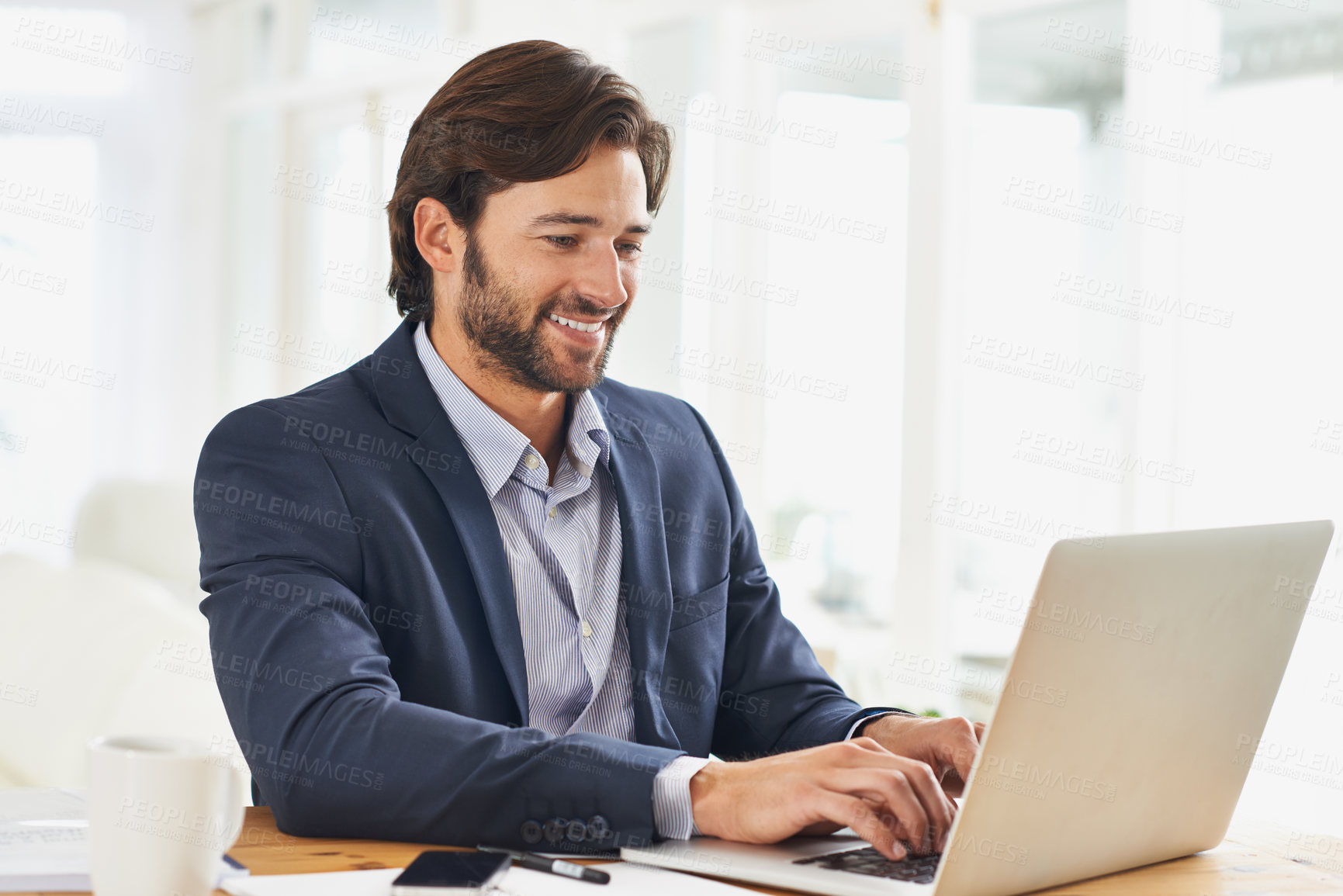 Buy stock photo A handsome businessman working on his laptop