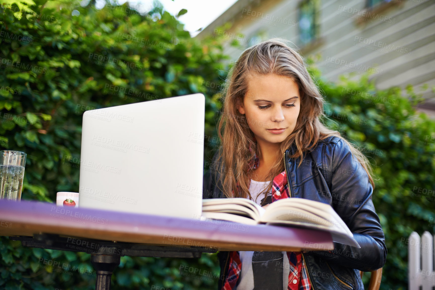 Buy stock photo Woman, book and laptop by cafe outdoors and sitting for reading, assignment or work. Young, female student and technology for online, submission or document for research, project or college test