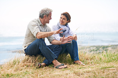 Buy stock photo Couple, face and happy at beach with relax, communication and peace for bonding, relationship or holiday. Mature, man and woman with smile, sitting and break in nature with travel, vacation and trust