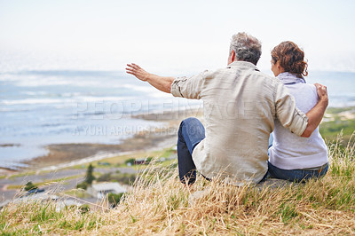Buy stock photo Old couple and pointing at nature on holiday, vacation or embrace with love or support in retirement. Back, man and woman together sightseeing on hill at beach or relax in environment and adventure
