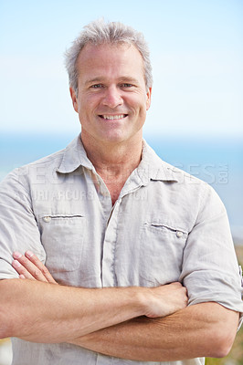 Buy stock photo Mature, man and arms crossed in portrait on holiday at beach to travel on adventure or vacation. Smile, outdoor and  person at the ocean or sea to relax in summer with blue sky, mockup and space