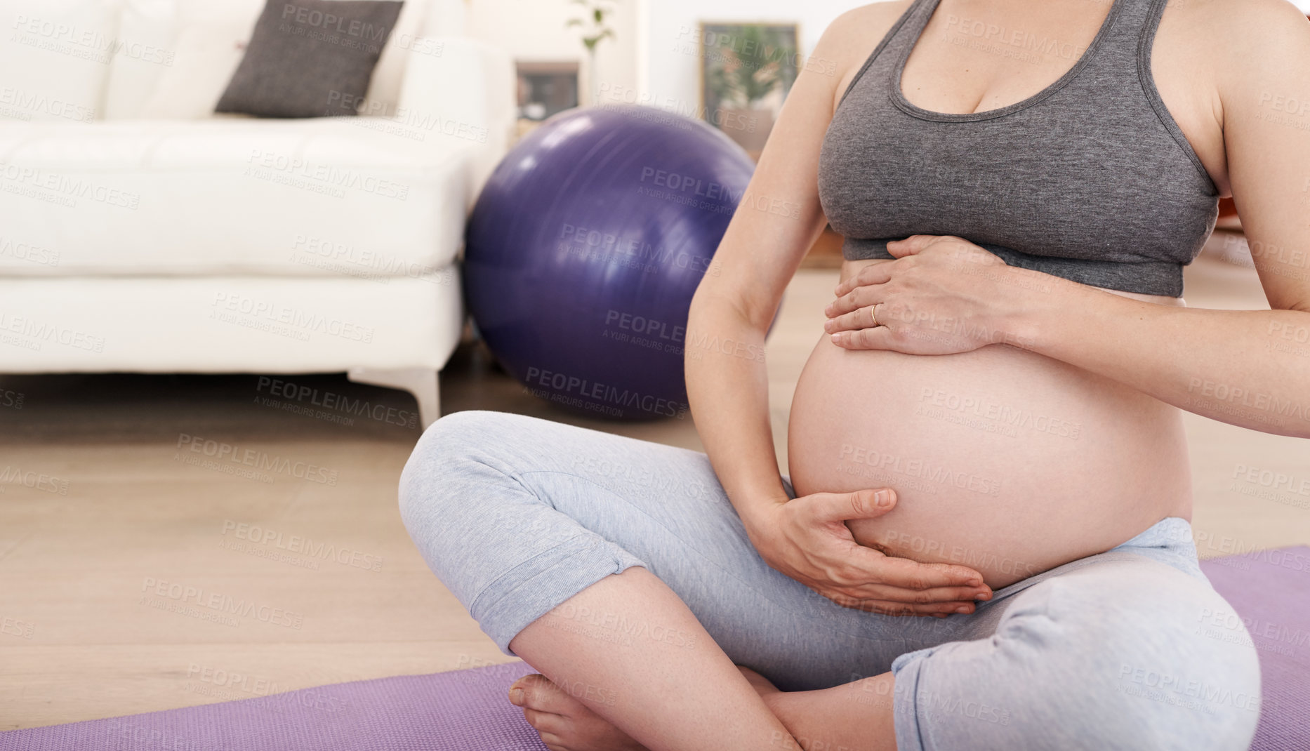 Buy stock photo Cropped shot of a pregnant woman exercising at home