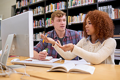 Buy stock photo Shot of two students working together at a computer in a university library