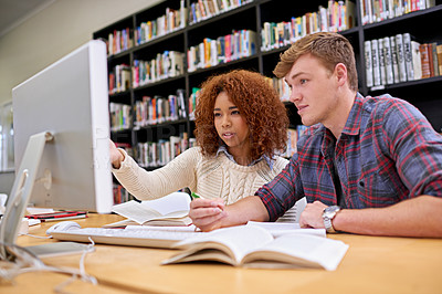 Buy stock photo Shot of two students working together at a computer in a university library