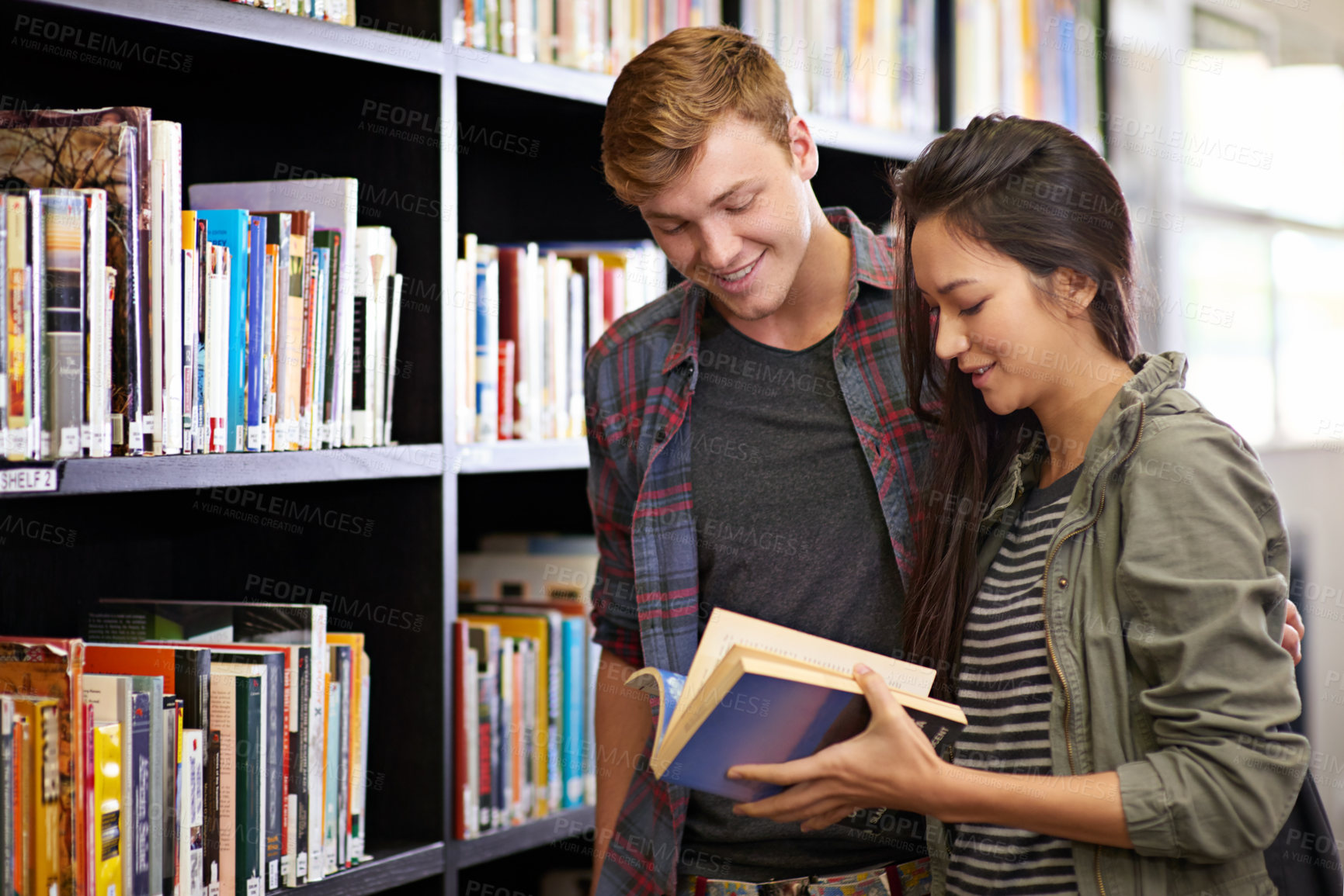 Buy stock photo Shot of a young couple studying together in the library