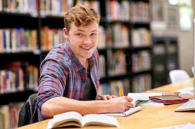 Buy stock photo Portrait of a male student studying at a table in a university library