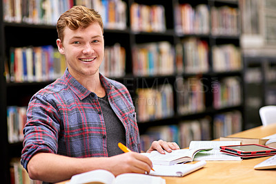 Buy stock photo Portrait of a male student studying at a table in a university library
