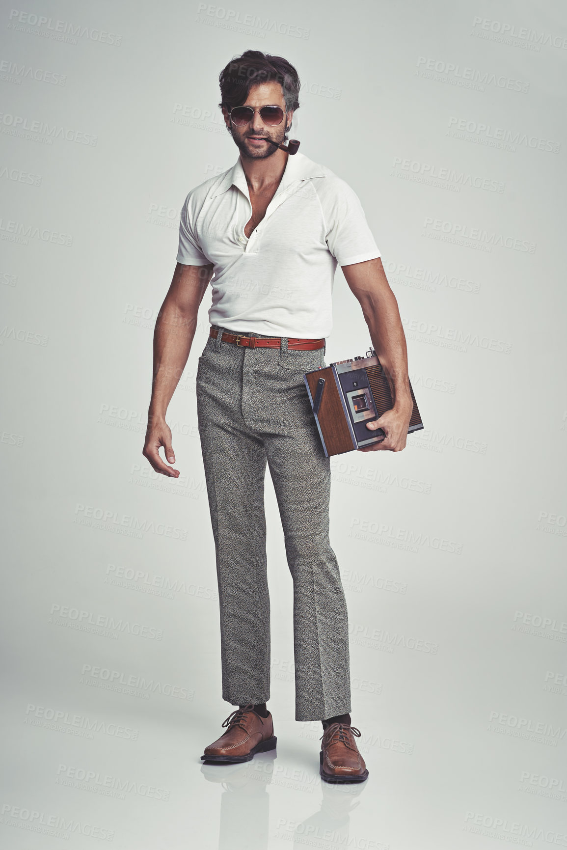 Buy stock photo A studio shot of a handsome man in retro 70s wear holding a cassette player