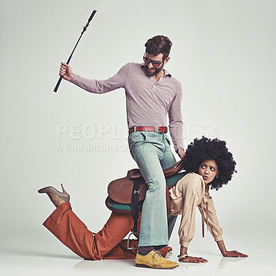 Buy stock photo Retro, man and woman or riding crop in studio with piggyback, portrait and funny face for vintage style. Friends, people and 70s outfit with hipster clothes or comic expression with white background