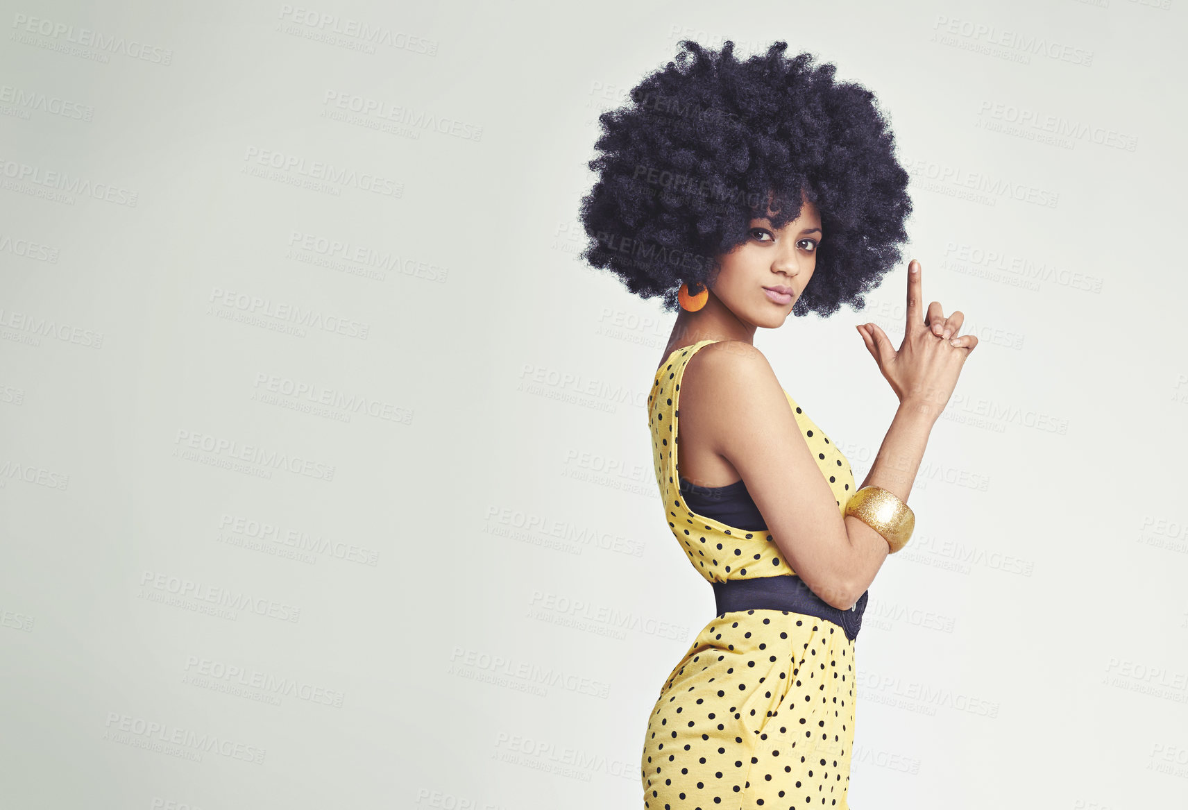 Buy stock photo Studio shot of a young woman wearing a jumpsuit making a gun sign with her hands