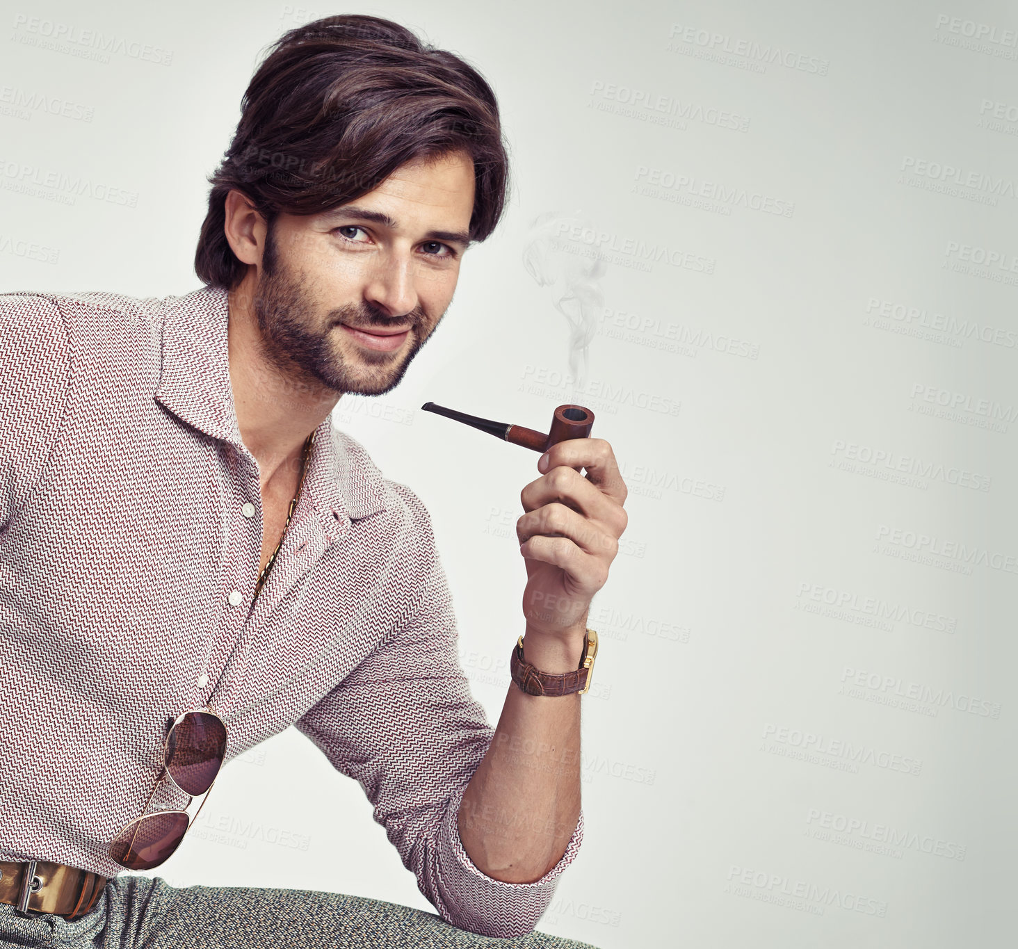 Buy stock photo A young man with 70s style sitting in the studio and smoking a pipe