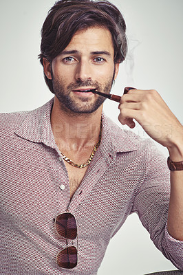 Buy stock photo A young man with 70s style sitting in the studio and smoking a pipe