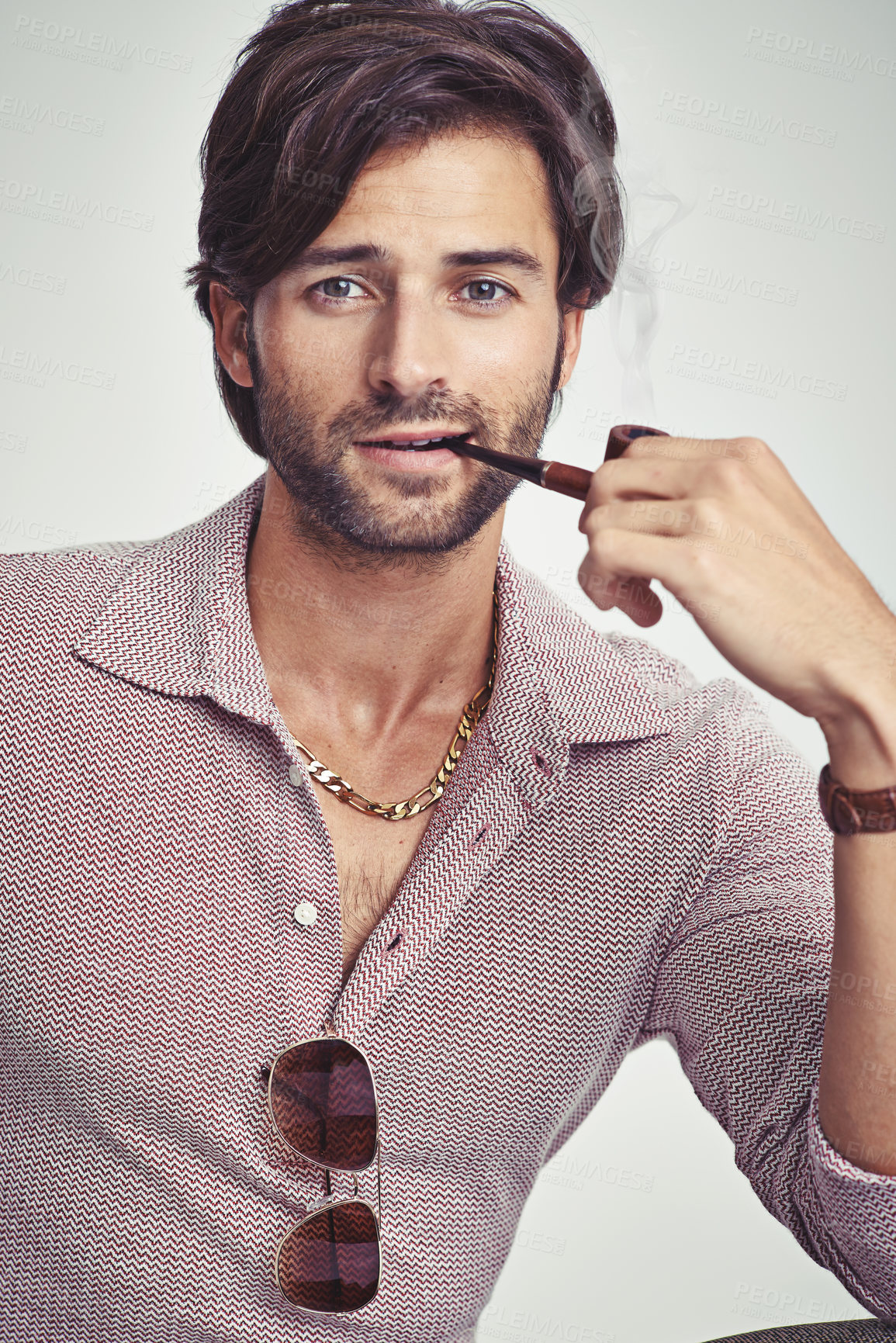 Buy stock photo A young man with 70s style sitting in the studio and smoking a pipe