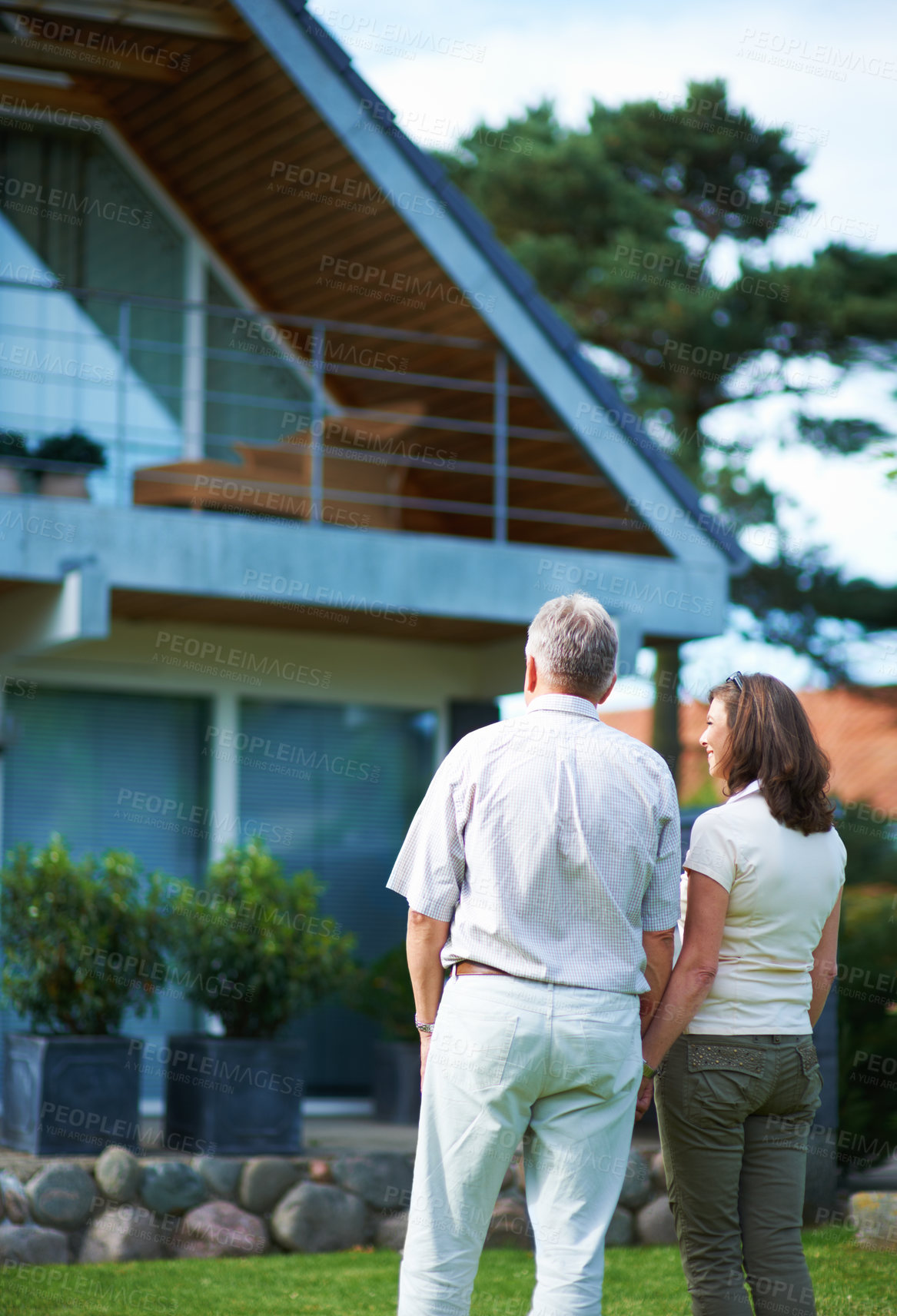 Buy stock photo Rearview shot of a mature couple standing hand-in-hand in front of their home