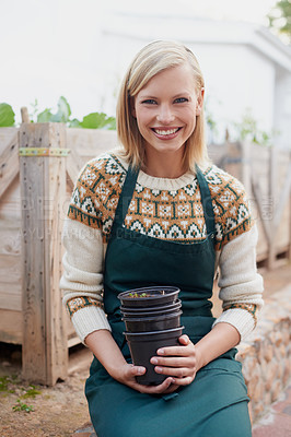 Buy stock photo A young woman holding pots in a nursery
