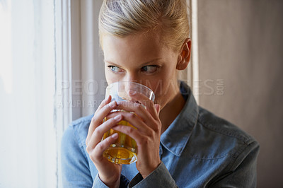 Buy stock photo A young woman drinking tea while standing at her window