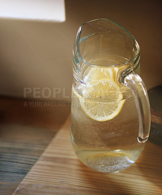 Buy stock photo Water, lemon and jug in kitchen for wellness or detox drink for hydration or natural vitamins, organic or counter. Beverage, sunshine and glass in home for healthy antioxidants, vitamin c or immunity