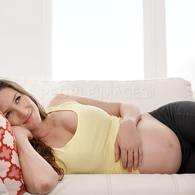 Buy stock photo Shot of a young pregnant woman lying on her living room sofa