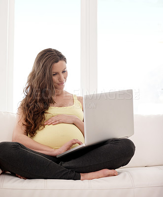 Buy stock photo Shot of a young pregnant woman working on her laptop at home