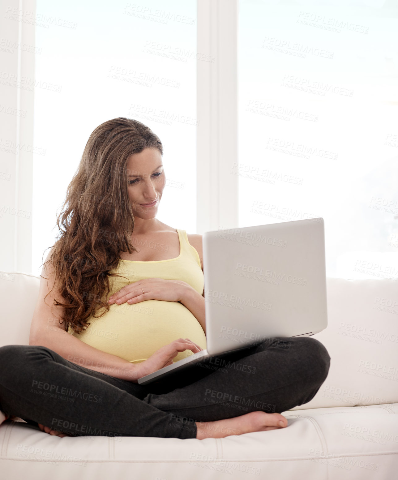 Buy stock photo Shot of a young pregnant woman working on her laptop at home