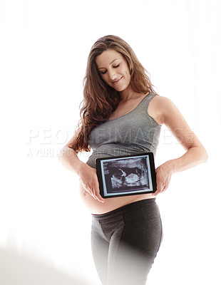 Buy stock photo Shot of a young pregnant woman holding a digital tablet with her ultrasound on the screen