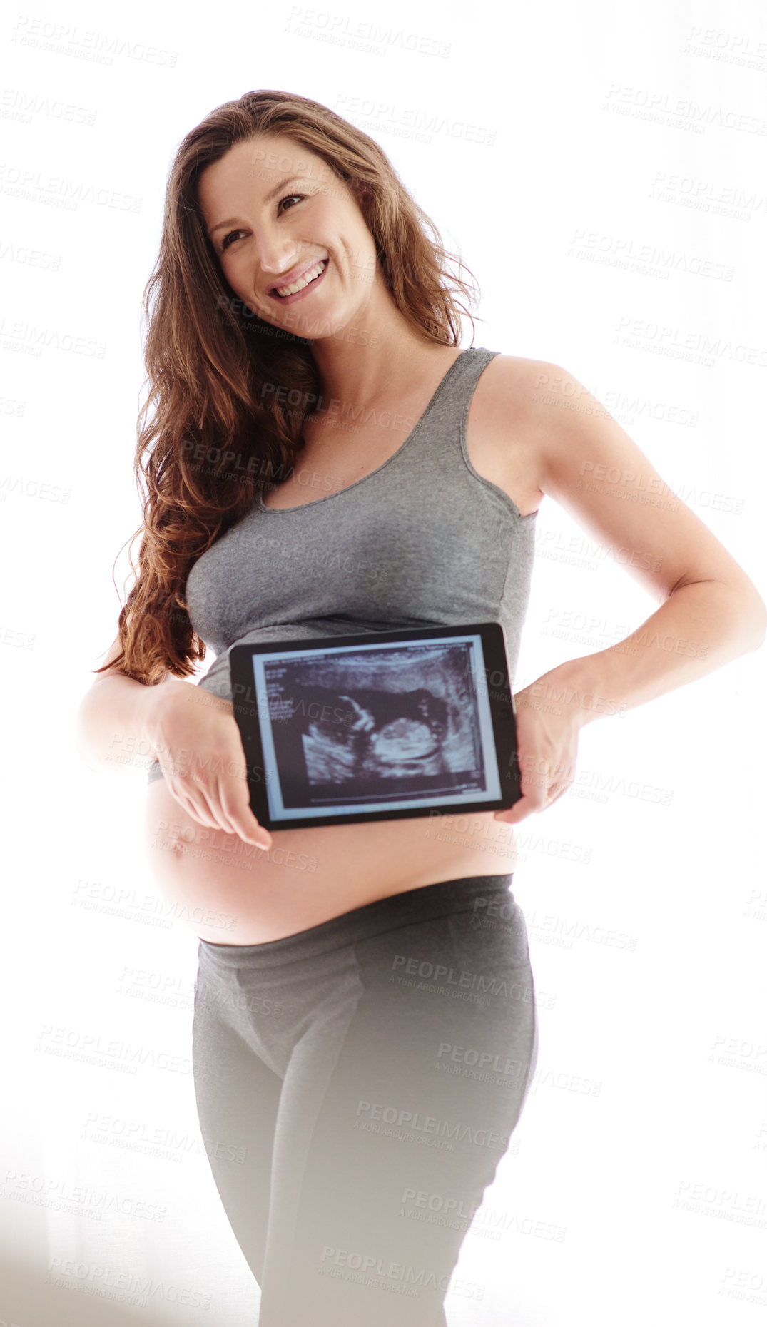 Buy stock photo Shot of a young pregnant woman holding a digital tablet with her ultrasound on the screen