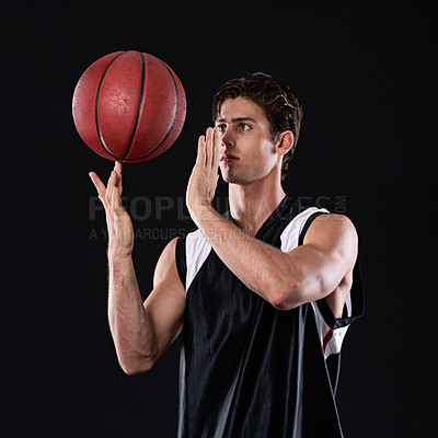 Buy stock photo A young athlete spinning a basketball on his finger against a black background