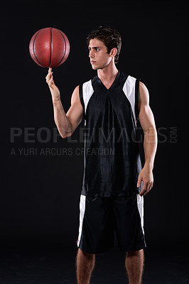 Buy stock photo A young athlete spinning a basketball on his finger against a black background