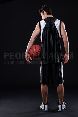 Buy stock photo Rearview studio shot of a basketball player holding a basketball against a black background