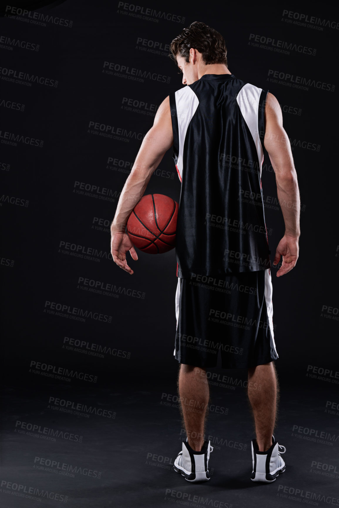 Buy stock photo Rearview studio shot of a basketball player holding a basketball against a black background