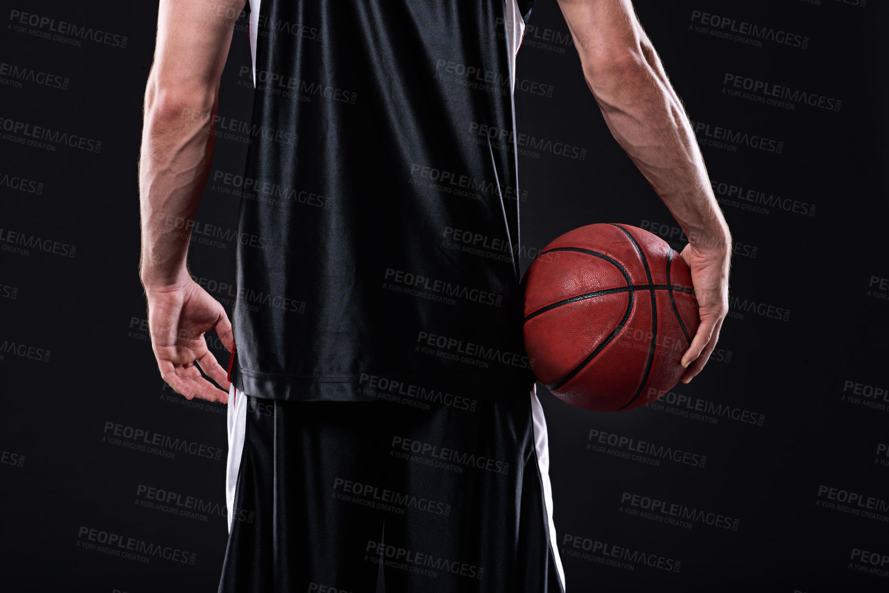 Buy stock photo Cropped rearview of a basketball player holding a basketball against a black background