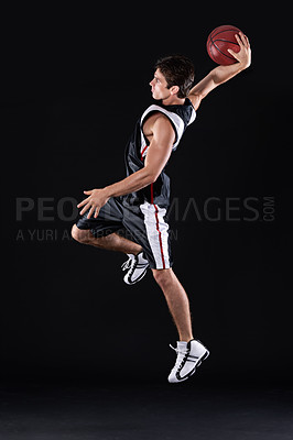 Buy stock photo Full length profile shot of a young male basketball player in action against a black background