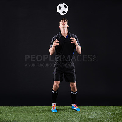 Buy stock photo Soccer, man and athlete with ball on head by grass on black background for training, exercise or fitness. Sport, field and male football player with equipment for skill, practice or workout in studio