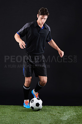 Buy stock photo Football, ball and man athlete on grass by black background for training, exercise or fitness. Sports, field and male soccer player with equipment for practice, workout or match on lawn in studio.