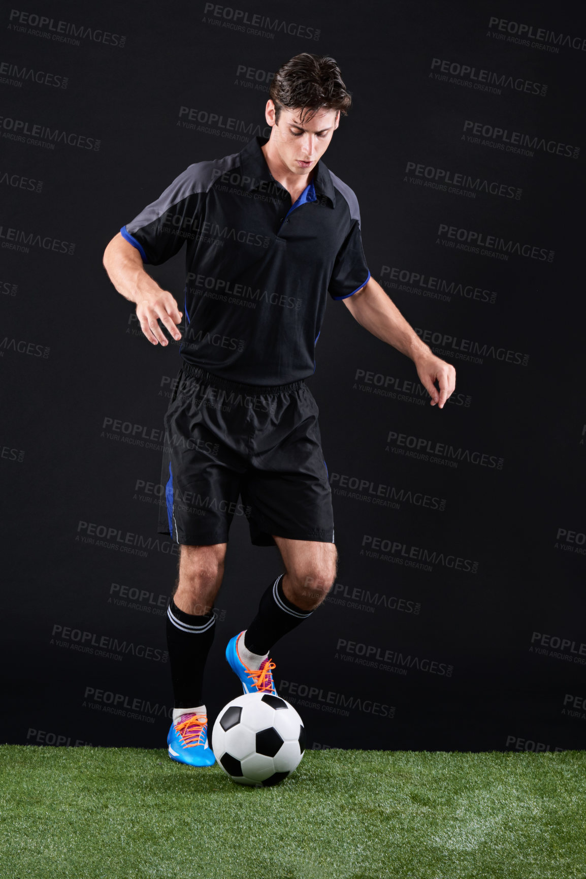 Buy stock photo Football, ball and man athlete on grass by black background for training, exercise or fitness. Sports, field and male soccer player with equipment for practice, workout or match on lawn in studio.