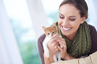 Buy stock photo Shot of an attractive young woman holding a kitten