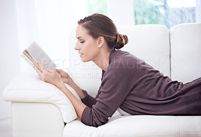 Buy stock photo Woman, book and reading on sofa to relax for story, novel and learning knowledge in living room at home. Profile, lady and fiction books for literature, hobby and comfortable break on couch in lounge